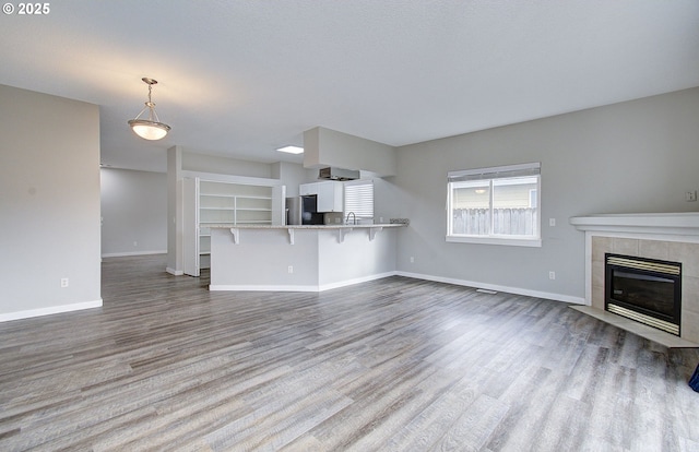 unfurnished living room featuring a tiled fireplace and hardwood / wood-style flooring