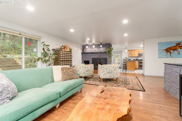 living room featuring light wood finished floors, a fireplace, and recessed lighting