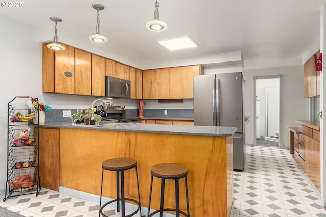 kitchen with stainless steel appliances, dark countertops, a peninsula, and light floors