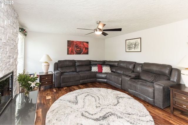 2416 SW 23rd Cir, Troutdale, OR 97060 - living area featuring ceiling fan, dark wood-type flooring, a stone fireplace, and a textured ceiling