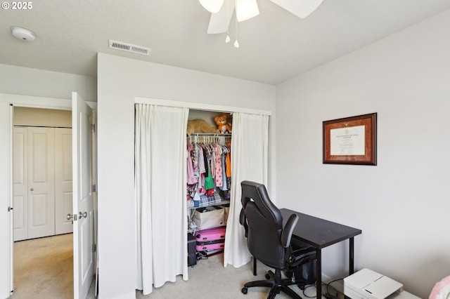 office space featuring light carpet, visible vents, and a ceiling fan