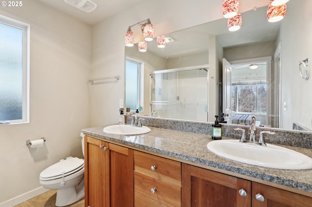 bathroom with a sink, a shower stall, toilet, and double vanity