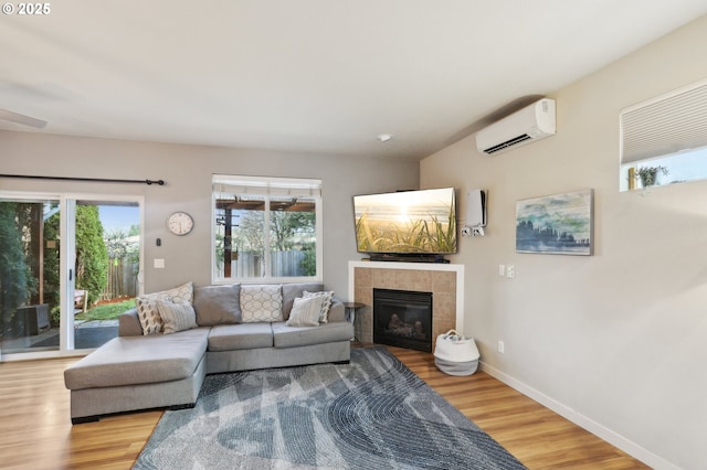 living room with a wall unit AC, plenty of natural light, and wood finished floors