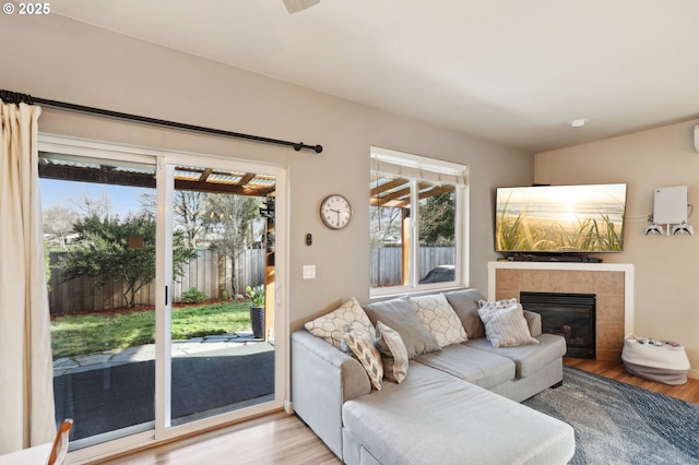 living area with light wood-style flooring and a tiled fireplace