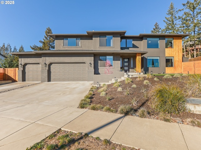 prairie-style home featuring an attached garage, brick siding, fence, driveway, and stucco siding