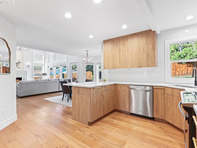 kitchen featuring light wood finished floors, open floor plan, a peninsula, stainless steel appliances, and light countertops