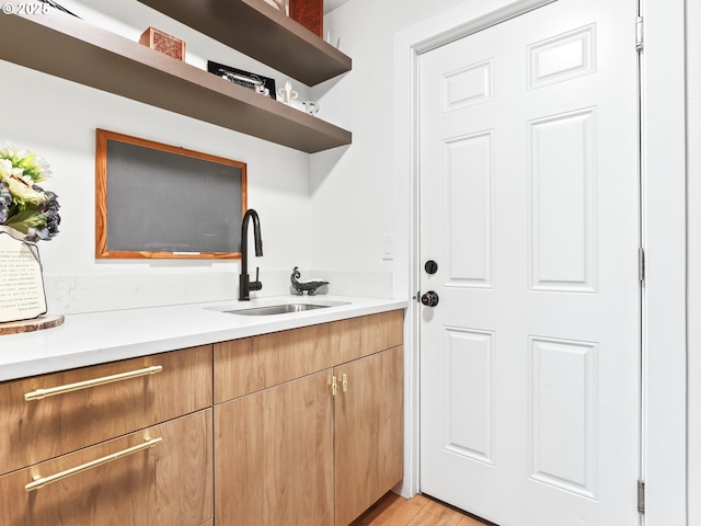 interior space featuring light countertops, a sink, light wood finished floors, and open shelves