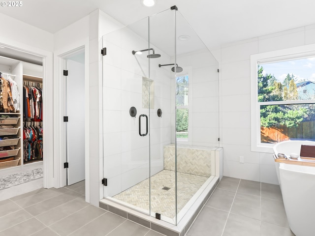 bathroom with tile walls, a freestanding bath, a spacious closet, a shower stall, and tile patterned floors