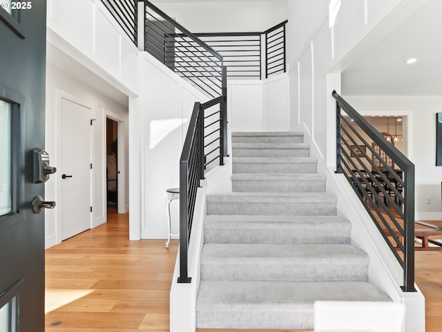 staircase with recessed lighting, a high ceiling, and wood finished floors