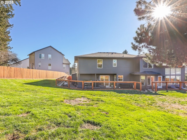 back of property with a lawn and fence