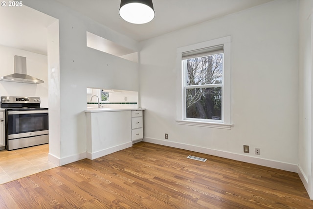 4903 SE Haig St, Portland, OR 97206 - kitchen with stainless steel electric range, wall chimney exhaust hood, light wood-style floors, and light countertops