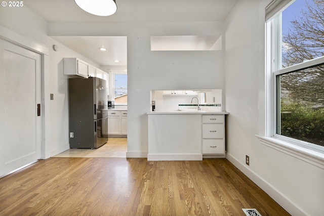 4903 SE Haig St, Portland, OR 97206 - kitchen with freestanding refrigerator, white cabinets, light wood-type flooring, plenty of natural light, and recessed lighting