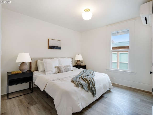 bedroom featuring an AC wall unit, multiple windows, and hardwood / wood-style floors