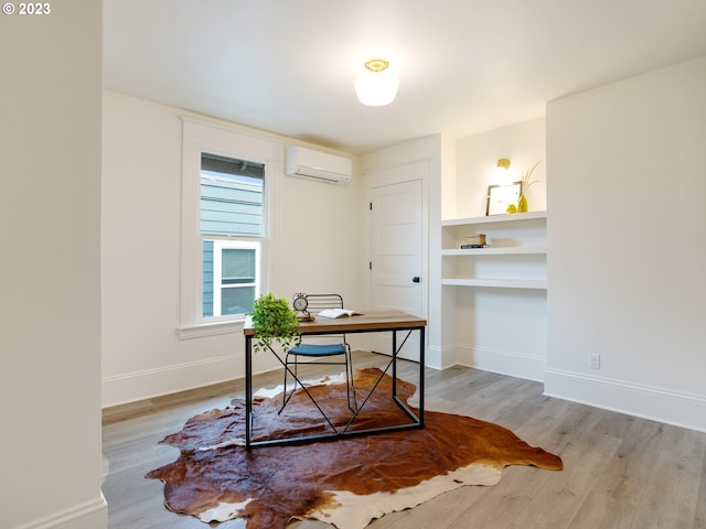 home office with light hardwood / wood-style flooring and a wall unit AC