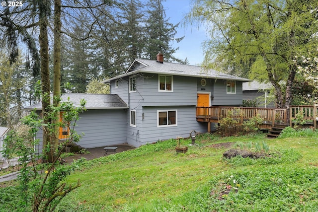 back of house featuring a chimney, a yard, a wooden deck, and roof with shingles