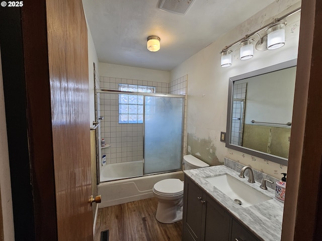 bathroom featuring toilet, shower / bath combination with glass door, wood finished floors, and visible vents