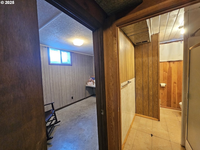 hall featuring wood walls and baseboards