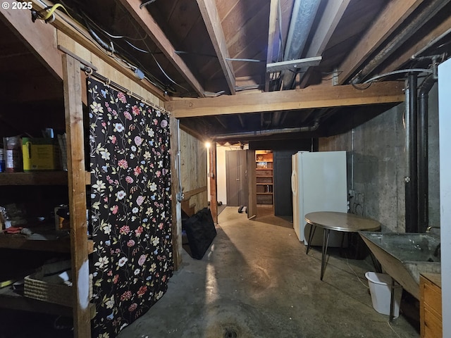 unfinished basement with freestanding refrigerator