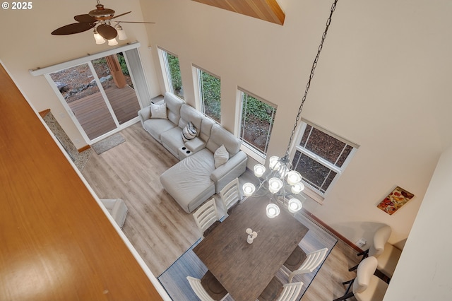 unfurnished living room featuring a towering ceiling, ceiling fan, baseboards, and wood finished floors