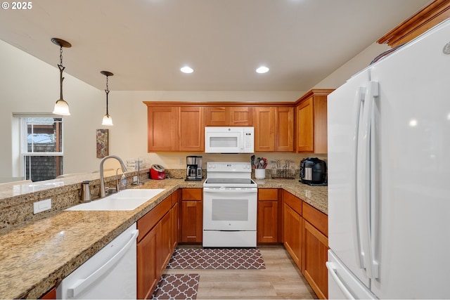 kitchen with white appliances, brown cabinetry, and a sink