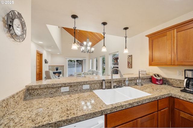 kitchen featuring a glass covered fireplace, decorative light fixtures, a sink, and lofted ceiling