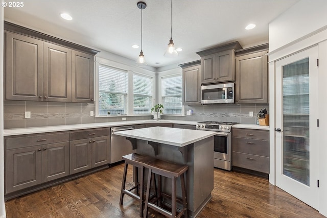 kitchen with a breakfast bar, dark wood-style floors, a kitchen island, and stainless steel appliances