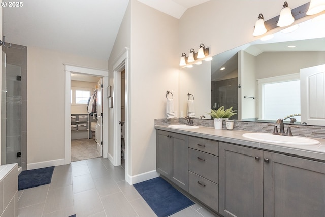 full bathroom with double vanity, vaulted ceiling, a stall shower, and a sink