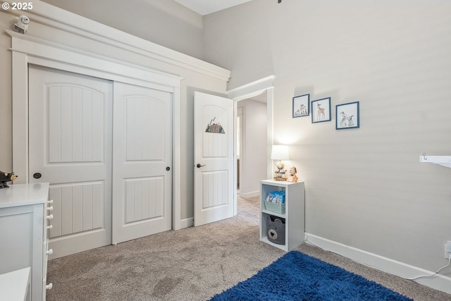 carpeted bedroom featuring a closet and baseboards