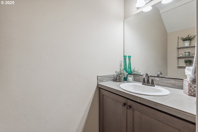 bathroom with vanity, vaulted ceiling, and tasteful backsplash