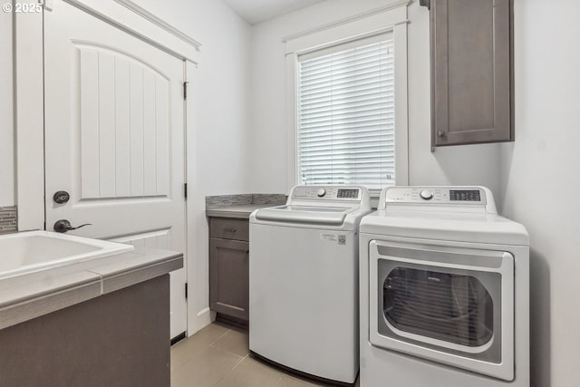 laundry room featuring light tile patterned flooring, cabinet space, and separate washer and dryer