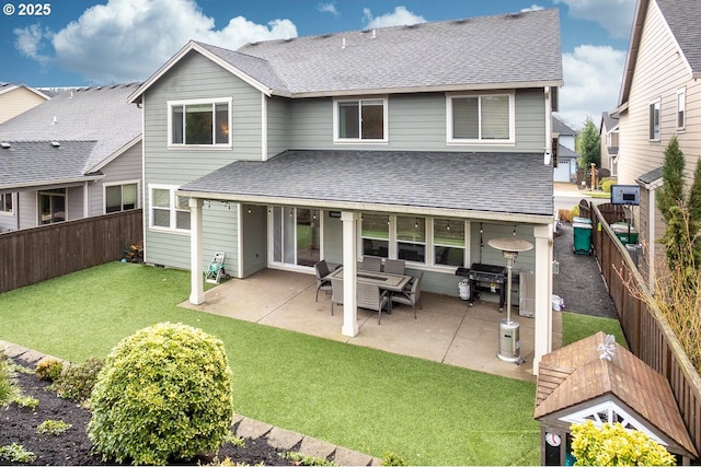 rear view of house featuring a yard, a patio, roof with shingles, and a fenced backyard