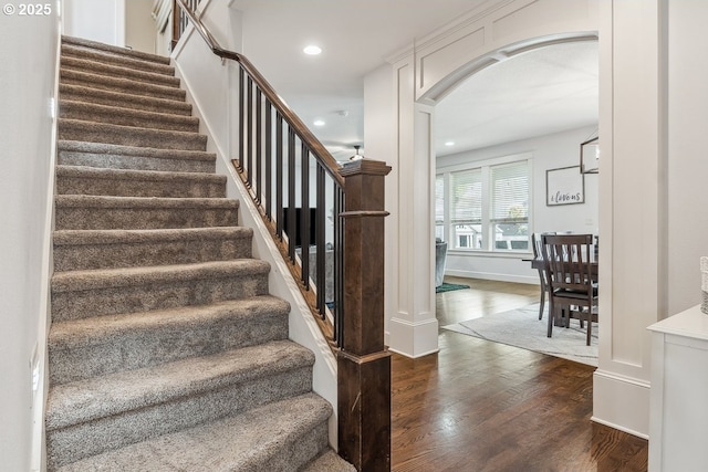 stairs with recessed lighting, wood finished floors, arched walkways, and baseboards