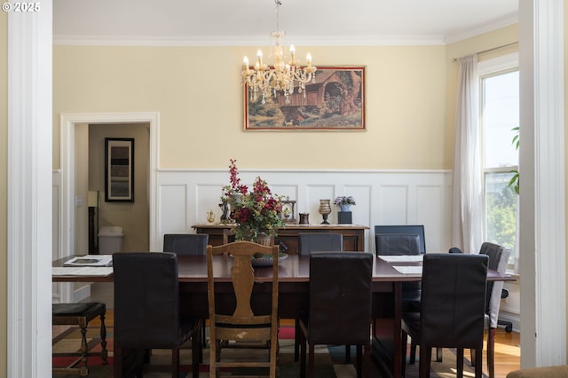 dining room with an inviting chandelier, hardwood / wood-style floors, and crown molding