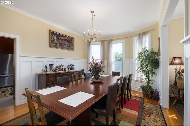 dining area featuring a notable chandelier, hardwood / wood-style flooring, and ornamental molding