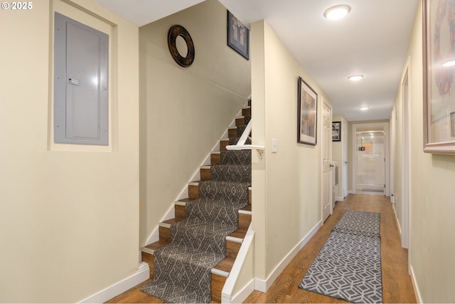 corridor with hardwood / wood-style flooring and electric panel