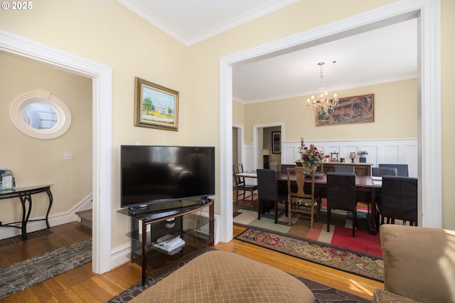 living room with wood-type flooring, a notable chandelier, and crown molding