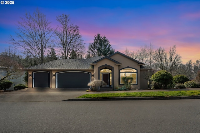 ranch-style home featuring a garage, concrete driveway, and stucco siding