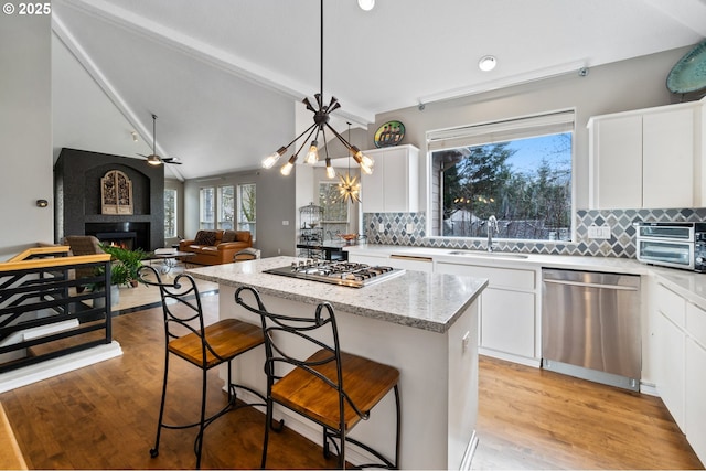 kitchen with tasteful backsplash, appliances with stainless steel finishes, a kitchen island, and a sink
