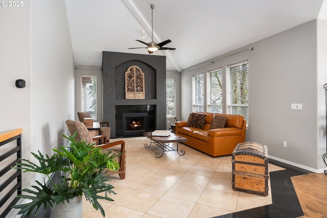 living area with light tile patterned floors, a large fireplace, ceiling fan, baseboards, and vaulted ceiling with beams