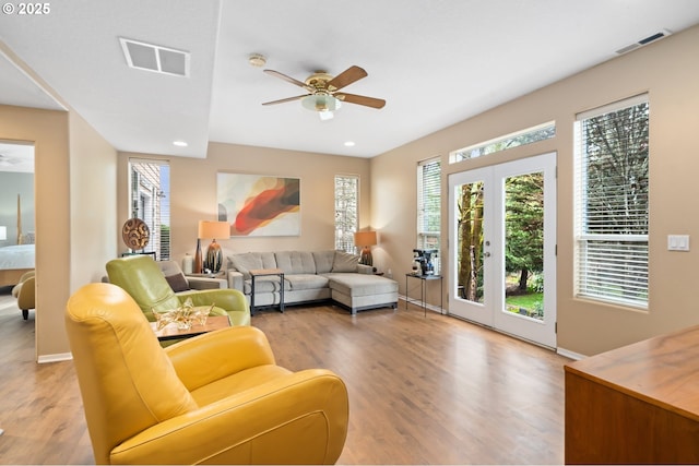 living room with a ceiling fan, visible vents, a healthy amount of sunlight, and light wood-type flooring