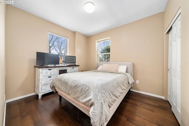 bedroom with dark wood-style floors, baseboards, and a closet