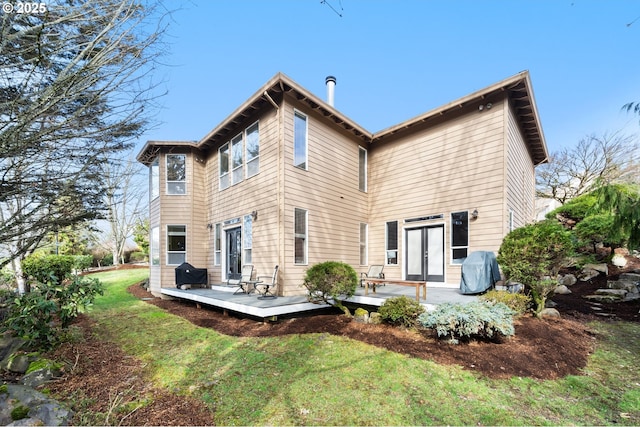 rear view of house featuring french doors, a wooden deck, and a yard
