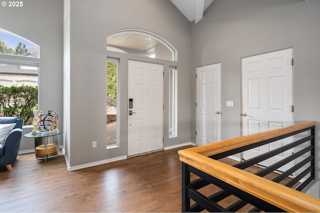 foyer entrance with wood finished floors, high vaulted ceiling, and baseboards