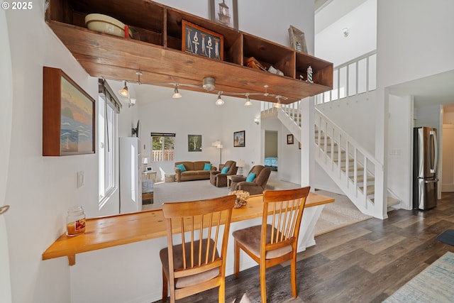 dining area featuring stairs, wood finished floors, and a towering ceiling