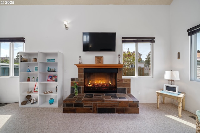 living area featuring carpet flooring, a lit fireplace, and a healthy amount of sunlight