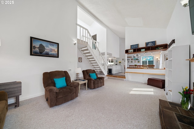 carpeted living area featuring stairs, high vaulted ceiling, and baseboards