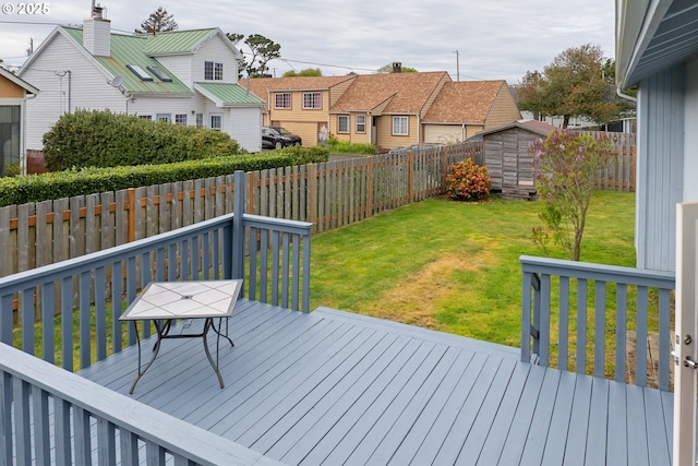 wooden terrace featuring a fenced backyard, a shed, a yard, and a residential view