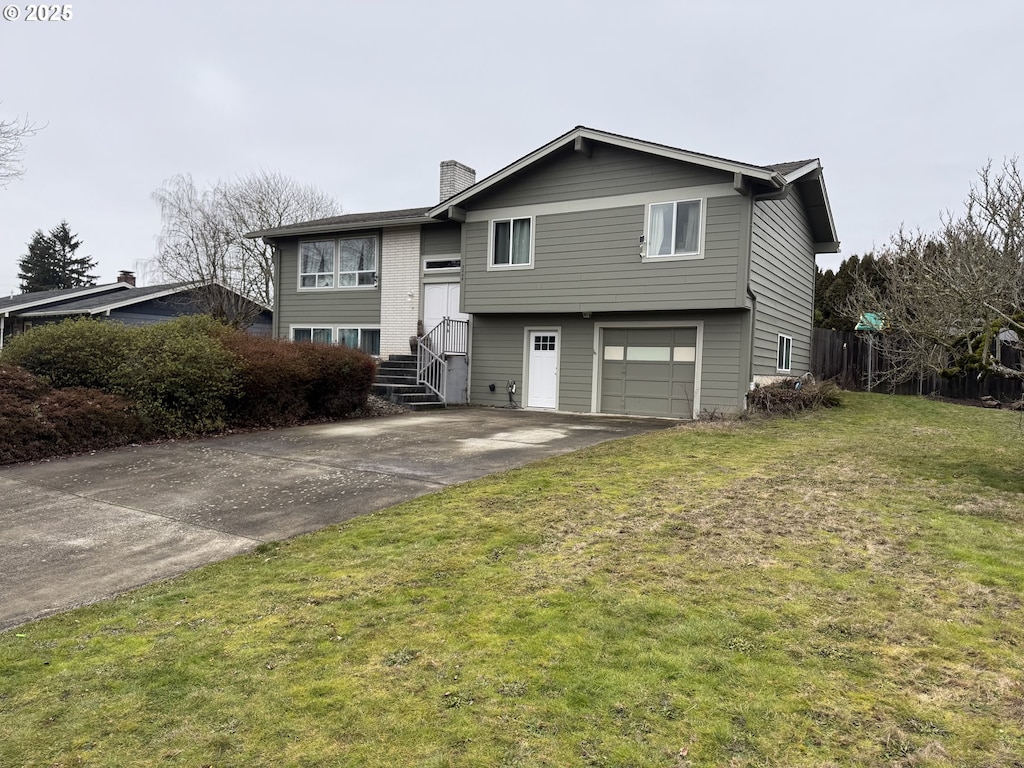 split foyer home with a garage, a front yard, a chimney, and driveway