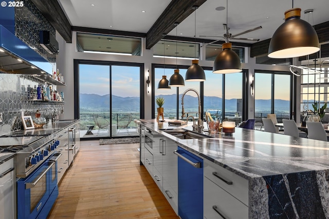 kitchen with white cabinets, double oven range, light hardwood / wood-style floors, a mountain view, and a spacious island