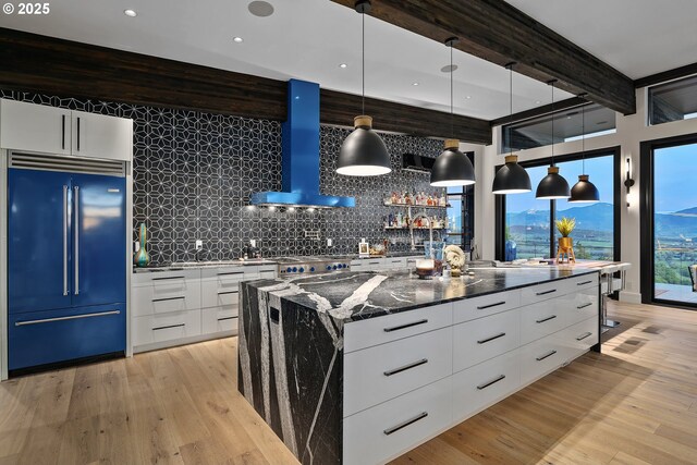 kitchen with pendant lighting, white cabinetry, a large island, exhaust hood, and paneled built in fridge